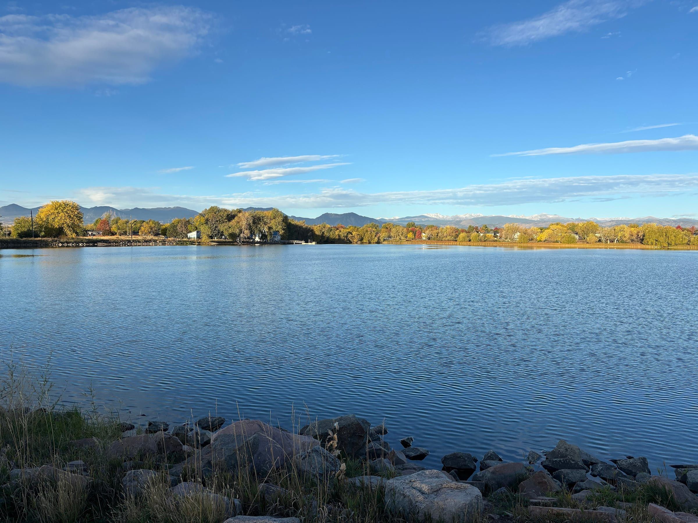 Waneka Lake in Lafayette on a clear morning, autumn trees along the far shore and low mountains beyond